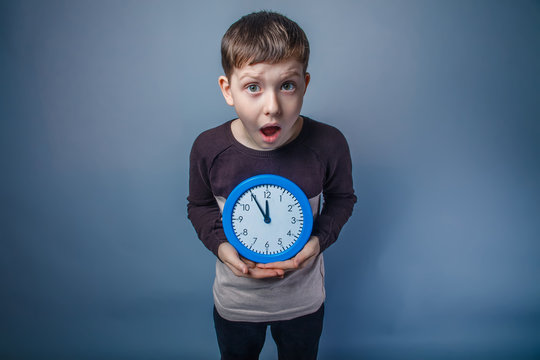 boy teenager European appearance holds a clock blue and opened h
