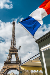 France flag over blue cloudy sky and Eiffel tower