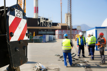 Crane pulley with workers in the background