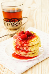 Pancakes with strawberry jam and tea on the wooden table
