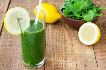Healthy green smoothie with spinach and lemon on wooden backroun