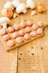 Raw meatballs on a wooden board with ingredients