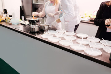 Chefs preparing food, empty plastic plates on the rack