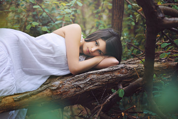 Beautiful woman posing on a dead tree