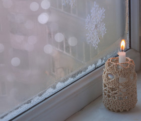 Winter window with burning candle
