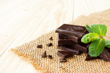 Dark chocolate with mint leaf on wooden background