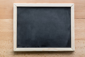 Horizontal shot of empty blackboard lying on wooden background