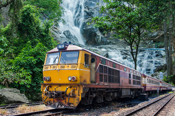 Obraz premium train passes through the mountain and cascade landscape