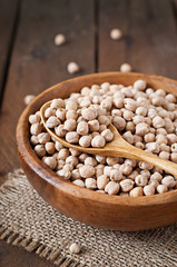 Chick-pea in wooden bowl on wooden background close up