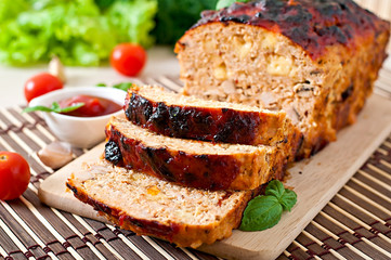 Homemade ground meatloaf with ketchup and basil