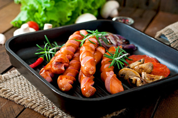Grilled sausages with vegetables on a frying pan