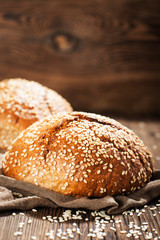 Fresh rye buns with sesame seeds on a wooden background