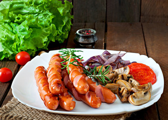 Fried sausages with vegetables on a white plate