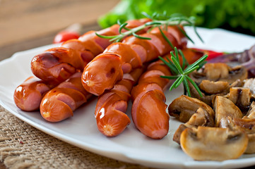 Fried sausages with vegetables on a white plate