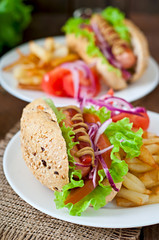 Hot Dogs with French fries on white plate, close-up