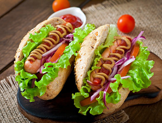 Hotdog with ketchup mustard and lettuce on wooden background