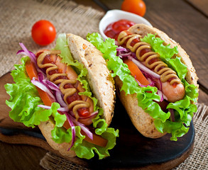 Hotdog with ketchup mustard and lettuce on wooden background
