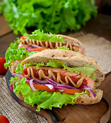 Hotdog with ketchup mustard and lettuce on wooden background