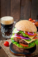 Big juicy hamburger with vegetables and beef on a wooden table