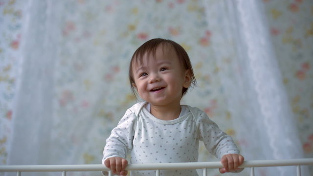 cute funny asian baby dancing on the bed