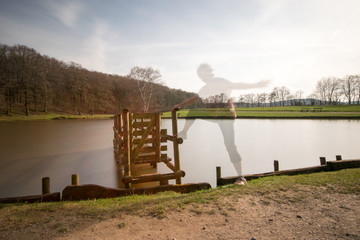 durchsichtige Person auf Holzsteg am See