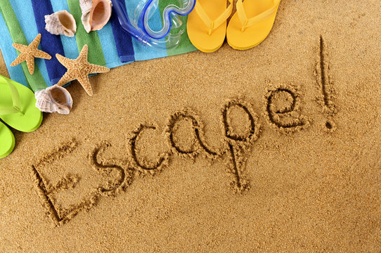 Escape word text message written in sand on a tropical beach with seashells and accessories summer holiday vacation photo