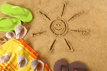 Smiling sun happy smiley face drawing drawn in sand on a tropical beach with seashells and...