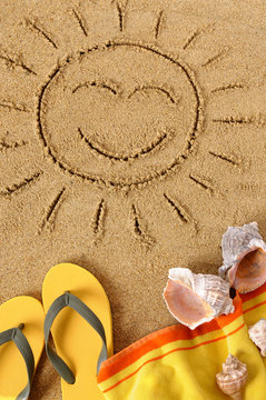 Smiling sun happy smiley face drawing drawn in sand on a tropical beach with seashells and accessories summer holiday vacation photo vertical