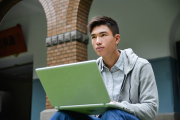 Portrait of Asian student sitting use laptop in her hand at campus