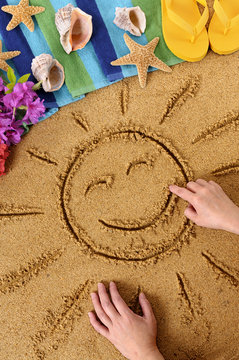 Smiling sun happy smiley face drawing drawn in sand with child hands on a hawaii beach with seashells and accessories summer holiday vacation photo vertical