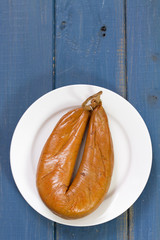 smoked sausage on plate on blue background