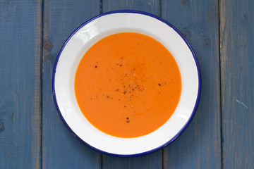 tomato soup in white plate on blue background