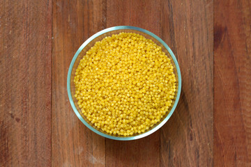 couscous in bowl on brown background