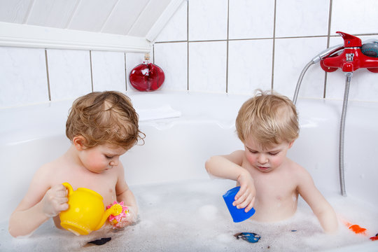 Twins having fun and playing with water by taking bath in bathtu