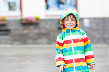 Little blond kid boy walking with big umbrella outdoors