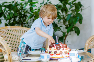 Little boy celebrating his birthday in home's garden with big ca