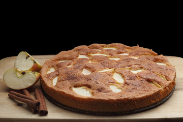 Apple sponge cake on the wooden board. Black background