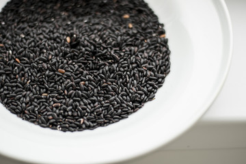 Black rice heap in ceramic dish top view close up