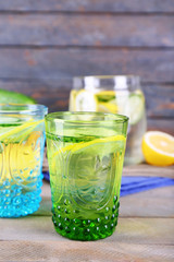 Fresh water with lemon and cucumber in glassware on wooden background