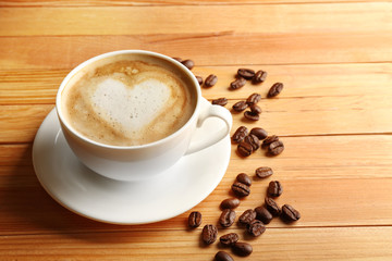 Cup of coffee latte art with grains on wooden background