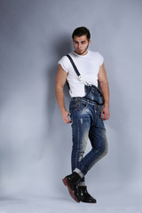 Man in jeans coveralls on gray background