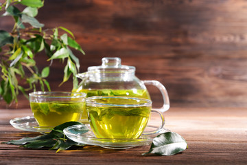 Fototapeta na wymiar Cups of green tea on table on wooden background