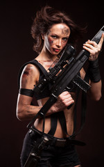 Fototapeta premium Beautiful young woman holding an automatic assault rifle. 