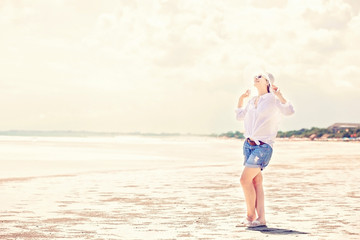 Beautifil young woman walking along the beach at sunny day