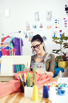 Young female fashion designer working on sewing machine