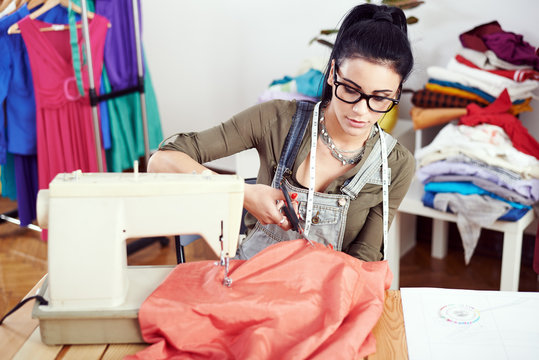 Young female fashion designer working on sewing machine