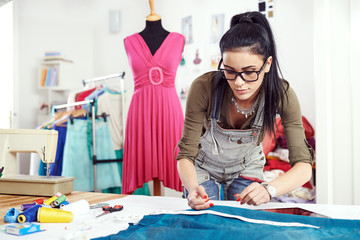 Young female designer measuring textile material