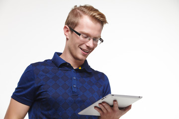 young blond man in glasses with a tablet in hands