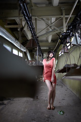 Fototapeta na wymiar brunette in a red dress in an abandoned factory premises