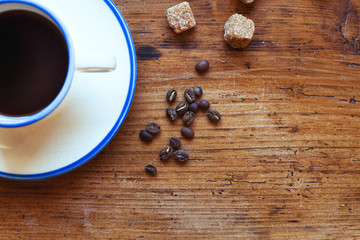 beautiful coffee grains and cup on wooden table in cafe, background with place for text